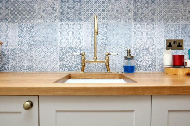 Brass kitchen taps against a patterned tiled splashback — Chiswick W4