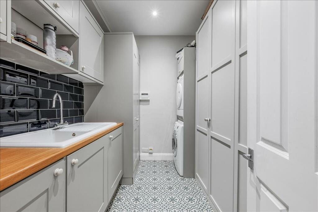 Utility room with grey cupboards, a timber worktop and patterned flooring