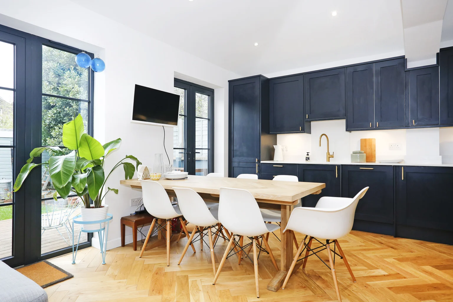 Navy kitchen and dining table beside garden doors — Ealing W13