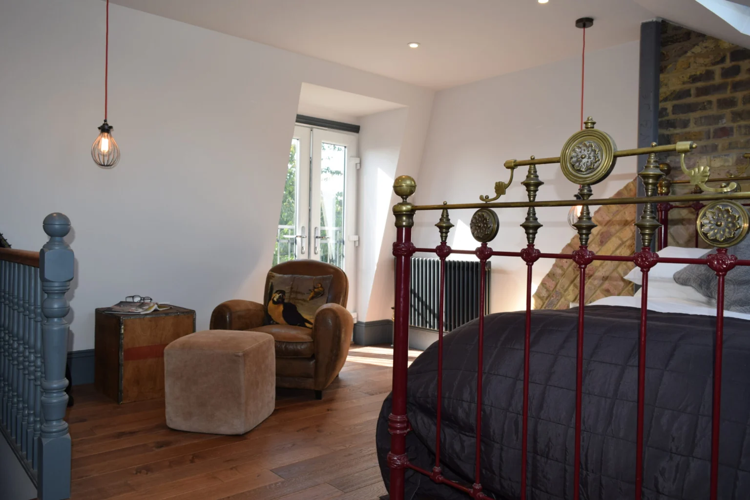 Loft bedroom with exposed brickwork and reading chair — Hammersmith W6 8HE