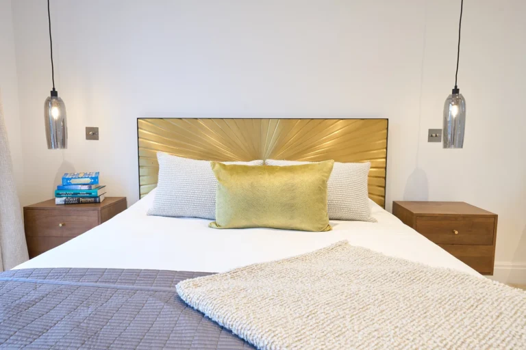 Modern bedroom with gold headboard and hanging lights — Chiswick W4