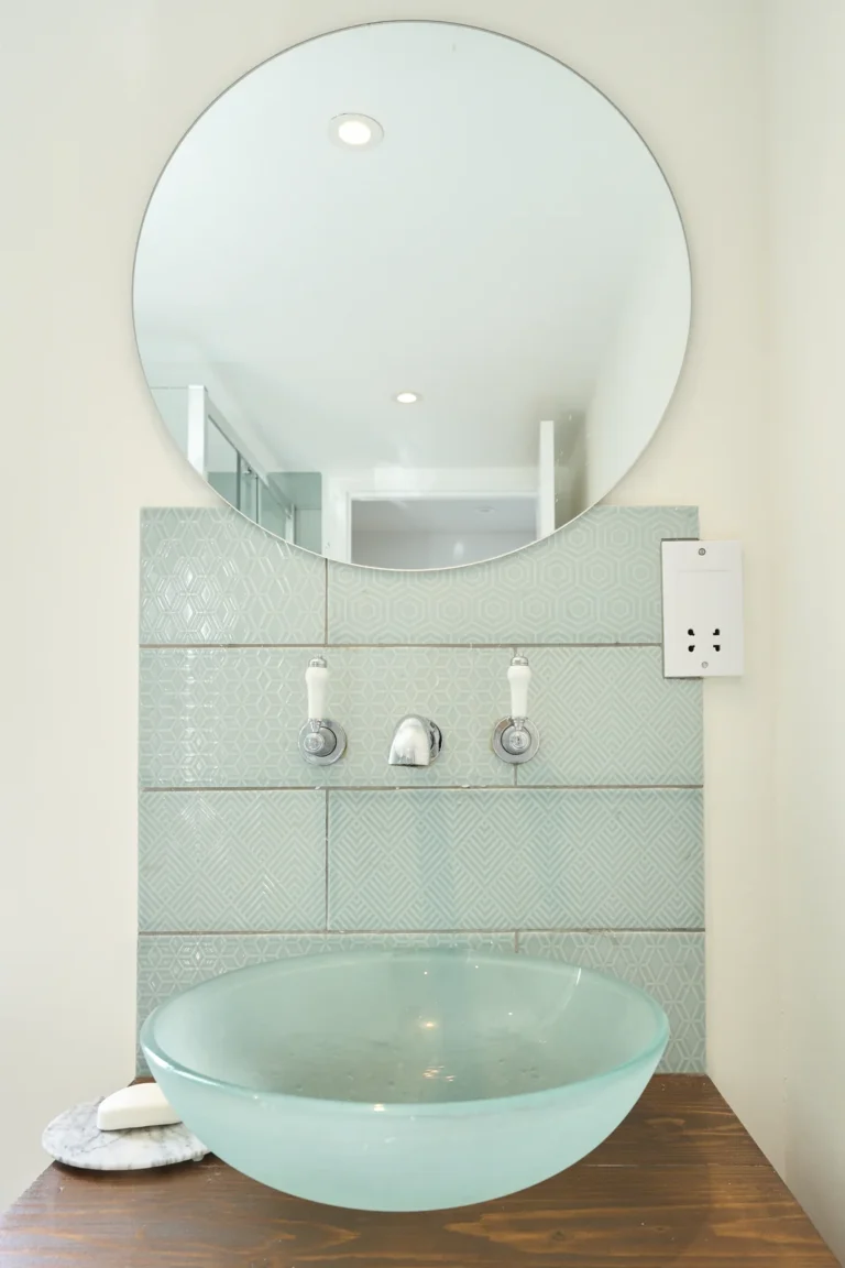 Modern bathroom sink with round mirror and tiles — Kennington SE17