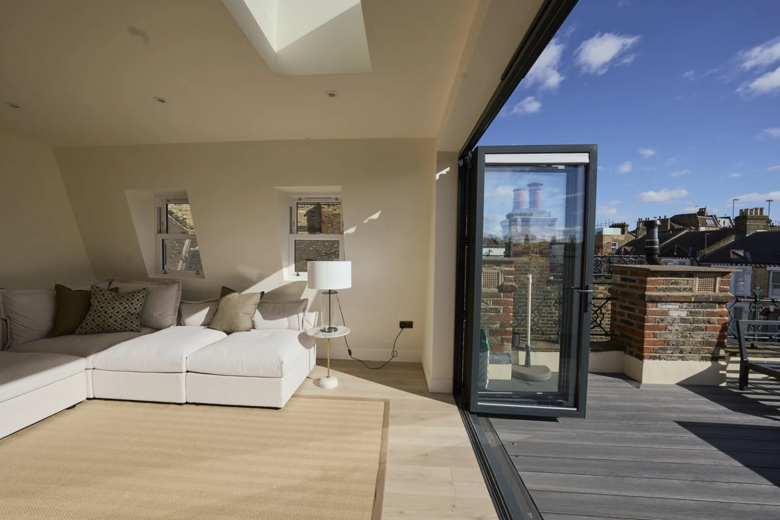 Loft seating area beside open folding doors and a roof terrace — Clapham SW11
