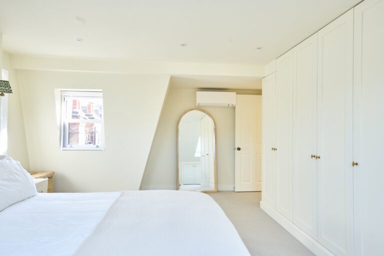 Loft bedroom with fitted white wardrobes and arched doorway — Clapham SW11