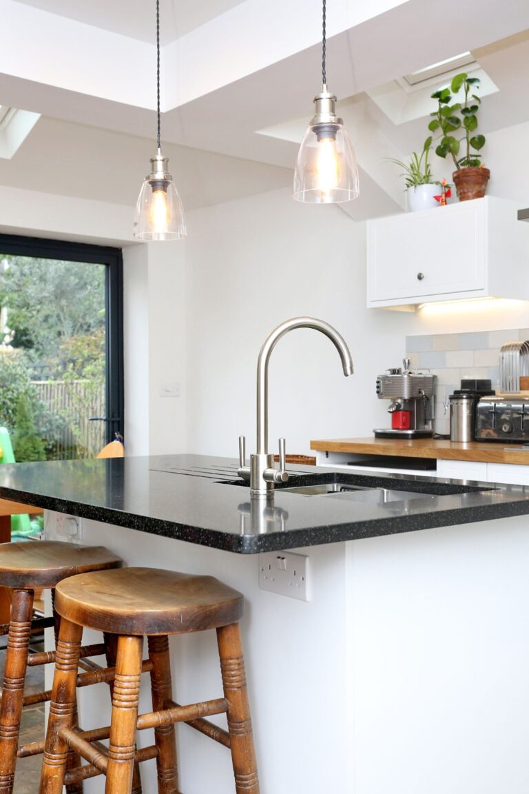 Modern kitchen with island, stools, sink, and pendant lights — Isleworth TW7