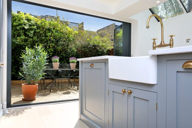 Modern kitchen with garden view through open doors — Hammersmith W6
