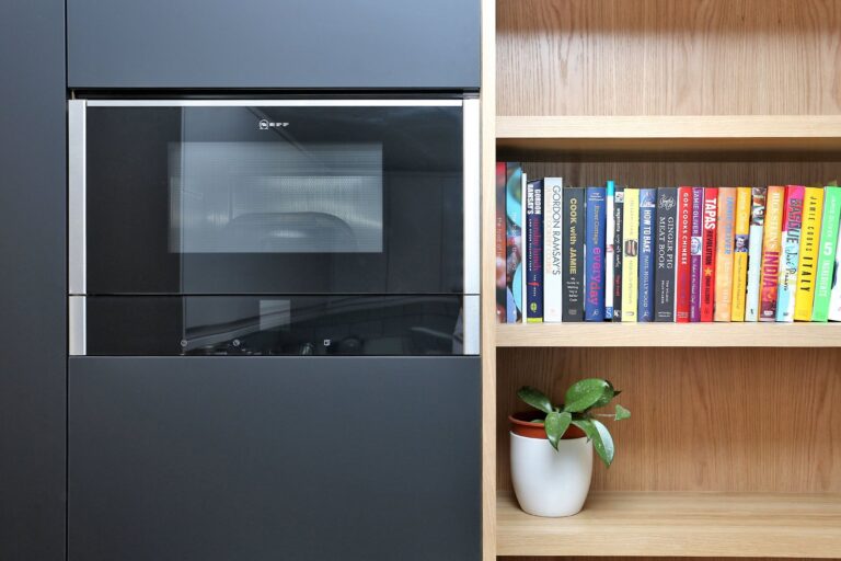 Microwave with bookshelf and plant nearby — Brentford TW8