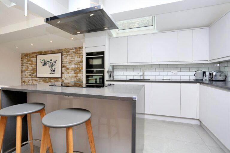 Modern kitchen with bar stools and brick wall art — Brentford TW8