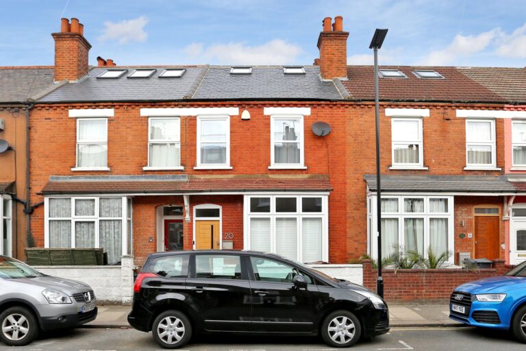 Red brick row houses and parked cars on street — Brentford TW8