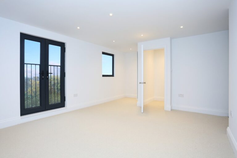 Empty loft room with black-framed balcony doors and an open doorway — Acton W3