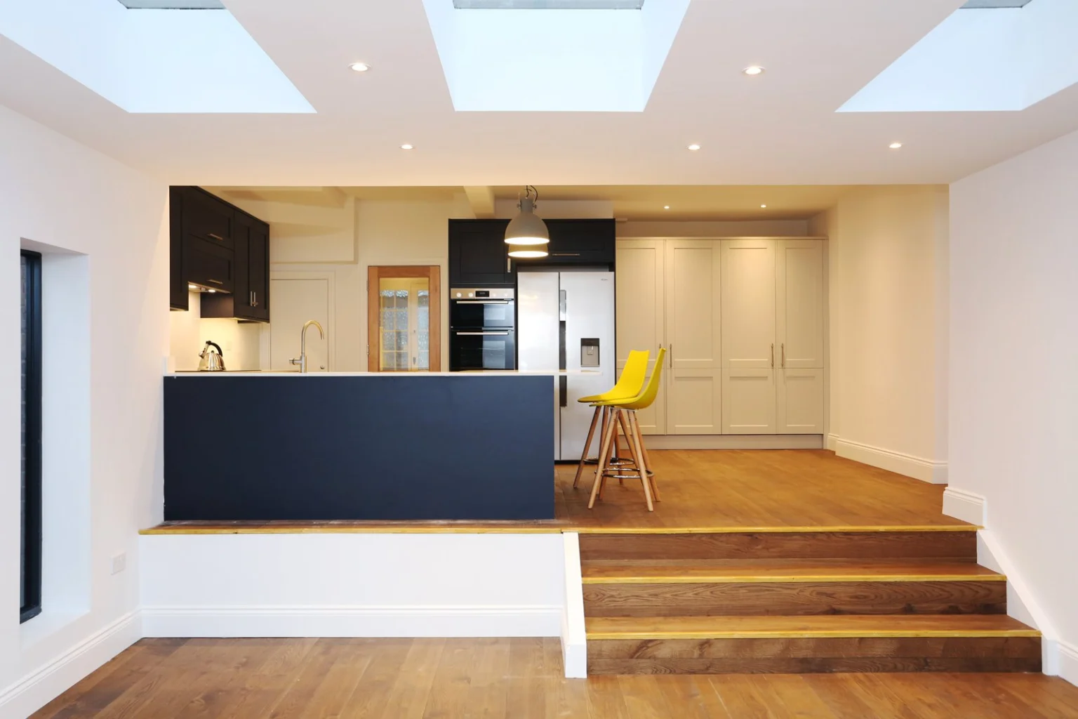 Modern kitchen with wood floor and yellow chairs — Acton W3