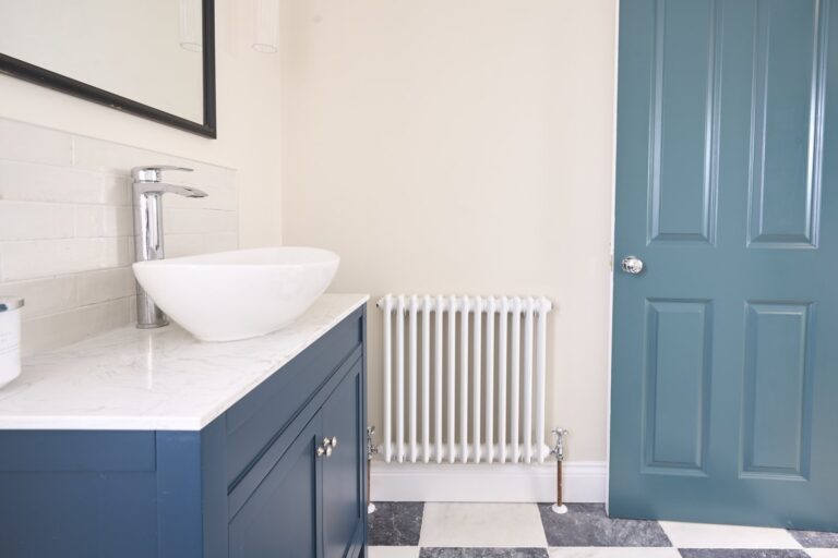 Modern bathroom with sink, radiator, and blue door — Balham SW12