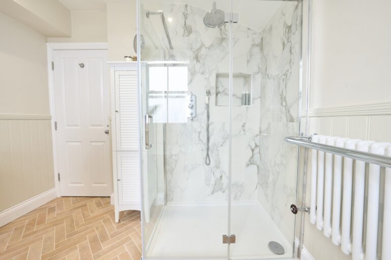 Glass shower enclosure against pale veined wall tiles — Balham SW12