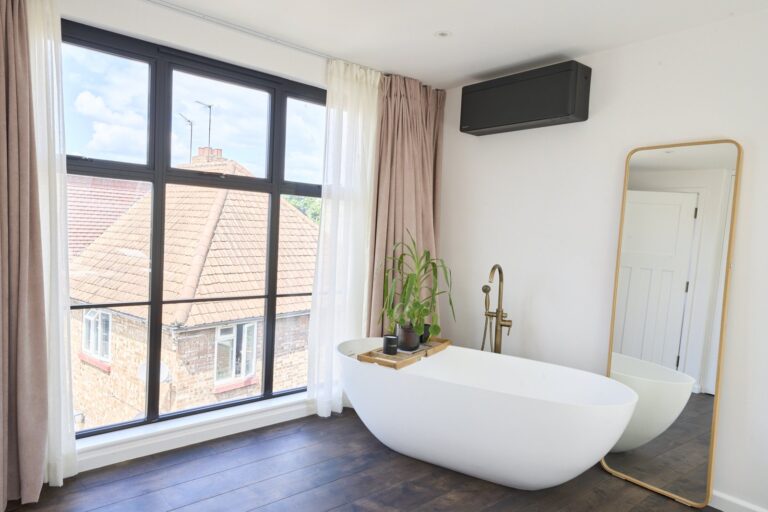Freestanding bath beside the rear window within the loft bedroom — Chiswick W4