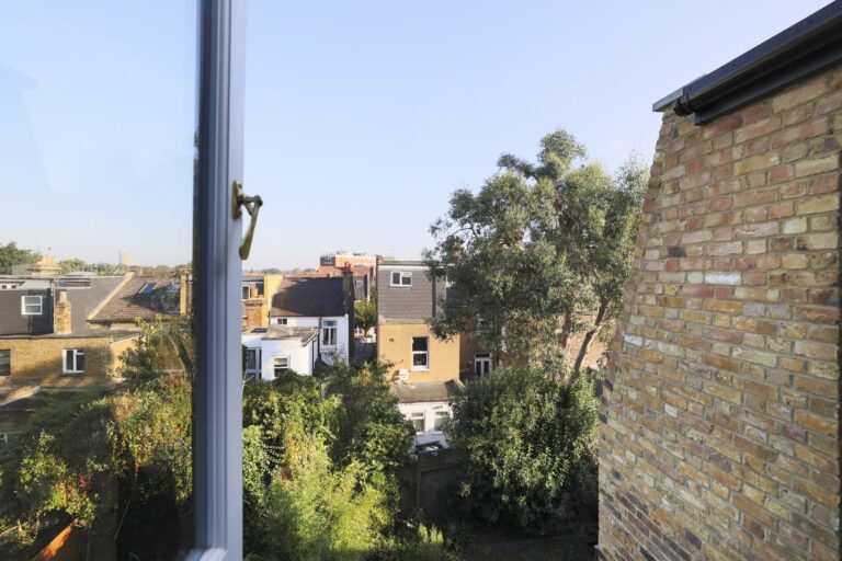 Urban view from a window with rooftops and trees — Acton W3
