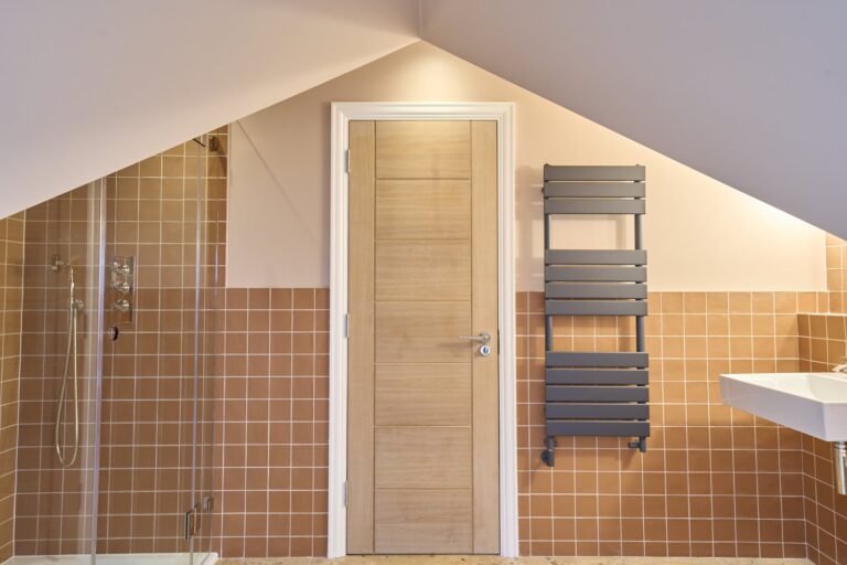 Modern bathroom with shower, door, and towel radiator — Ealing W5