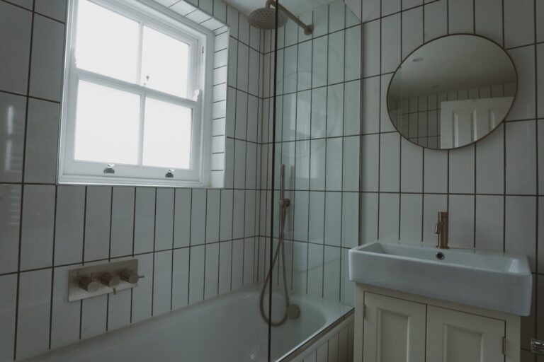 Modern bathroom with tiled walls and round mirror — Fulham SW6