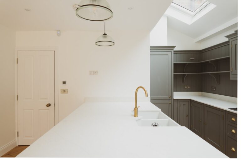 White kitchen island worktop with brass tap beneath rooflights — Fulham SW6