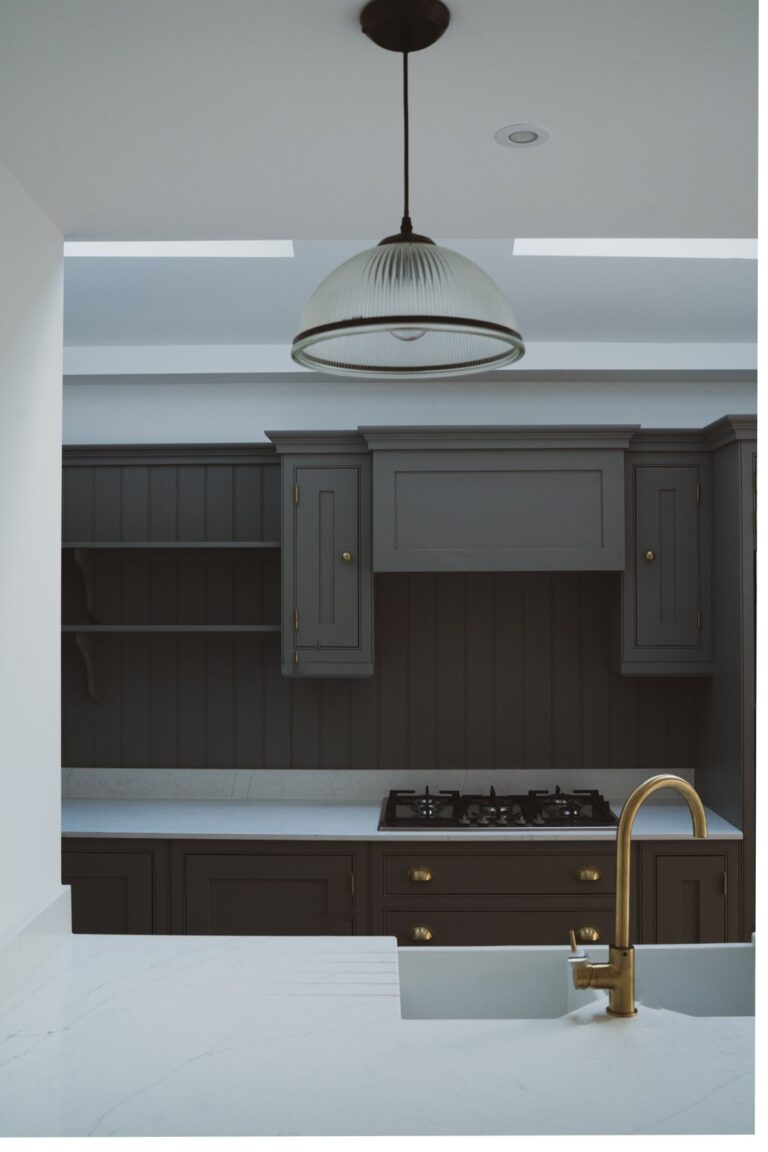 Modern kitchen with dark cabinets and brass faucet — Fulham SW6