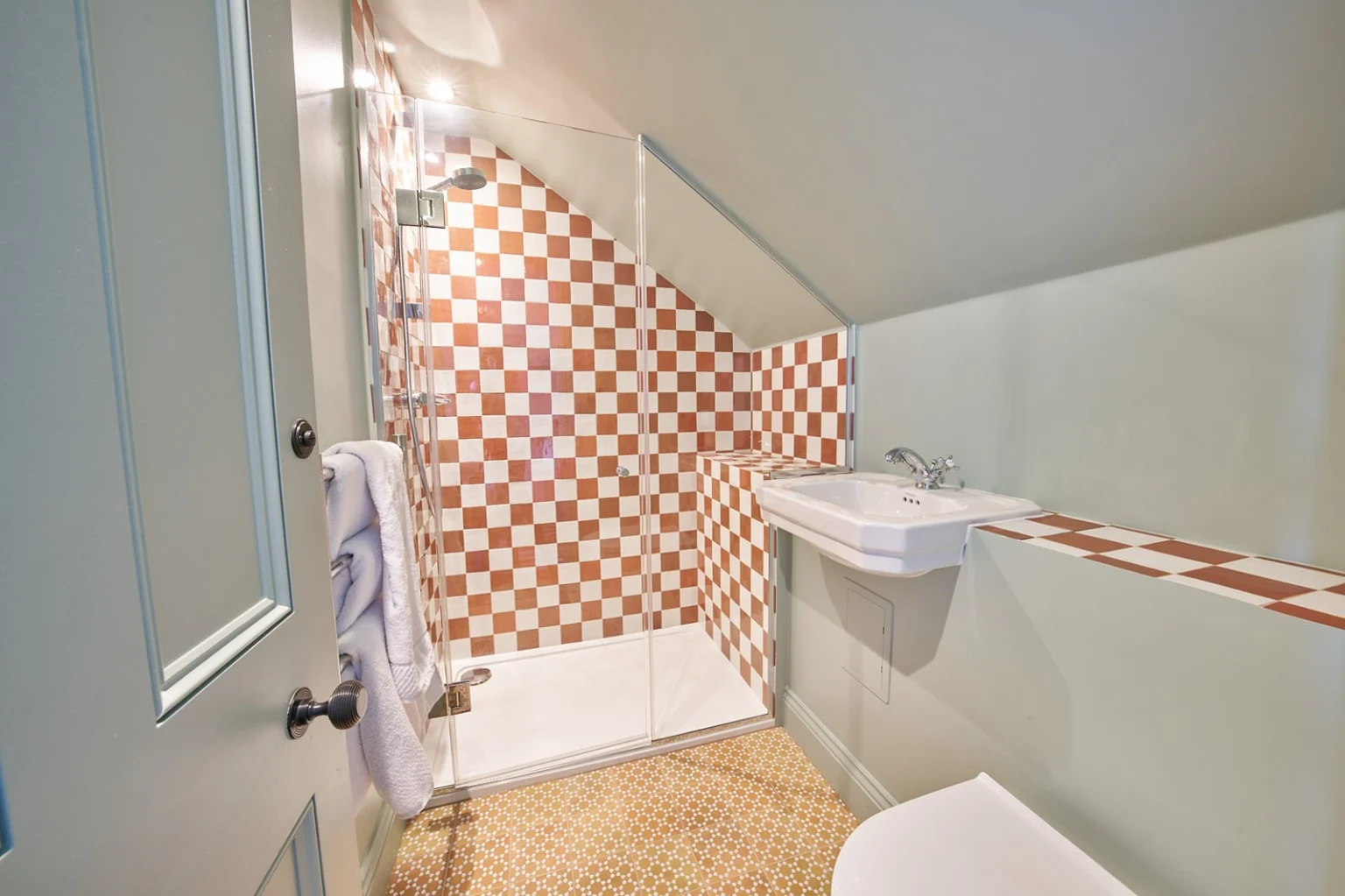 Cosy bathroom with checkered tile and glass shower — Kensington W10