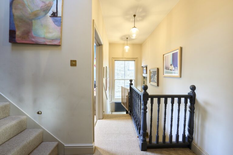 Interior hallway with staircase and framed artwork — Acton W3